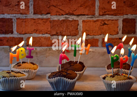 Delicious muffins-cupcakes whit burning happy birthday candles at brick wall as background/ Happy birthday celebration card/ Greeting card Stock Photo