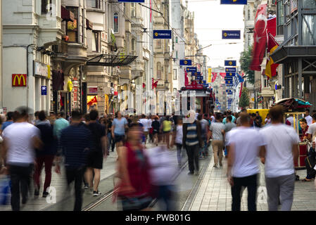 A busy street view of Istikal street with people walking past a long line of shops as the Taksim heritage tram goes past , Istanbul, Turkey Stock Photo