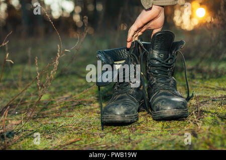 hiker old black boots standing on grass Hard travel concept Nature background Stock Photo