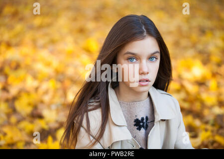 Happy young little girl in beige coat in autumn park Stock Photo