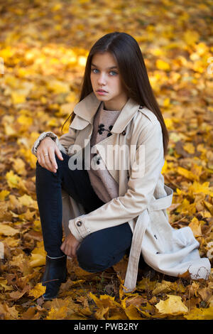 Happy young little girl in beige coat in autumn park Stock Photo