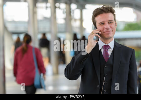 Businessman talking on mobile phone while thinking on train stat Stock Photo
