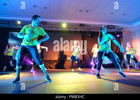 Instructors dancing energetically on stage during a Zumba class Stock Photo