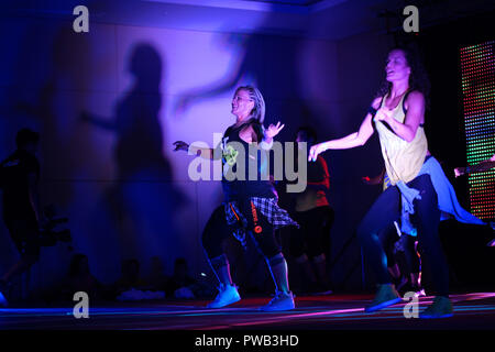 Instructors dancing energetically on stage during a Zumba class Stock Photo