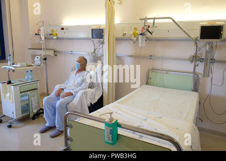 Patient wearing mask while sitting in a hospital bedroom Stock Photo