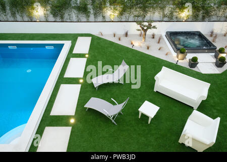 Aerial view of a backyard with a swimming pool, a jacuzzi, two deckchairs and assorted outdoors furniture Stock Photo