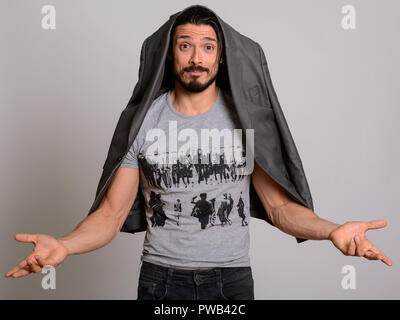 Studio shot of handsome man looking confused with jacket hanging Stock Photo