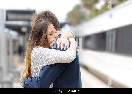 Sad couple hugging saying goodbye before train travel Stock Photo