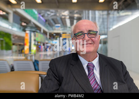 Overweight senior businessman lounging around the airport of Ban Stock Photo