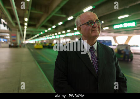 Overweight senior businessman lounging around the airport of Ban Stock Photo