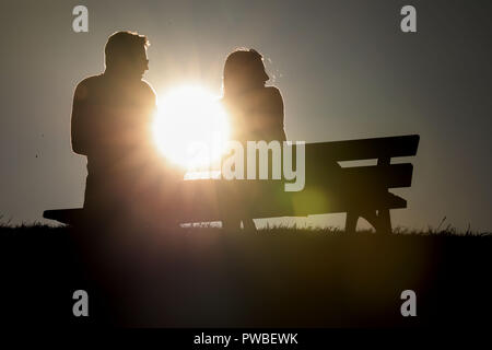 Oberwiesenthal, Saxony. 14th Oct, 2018. A man and a woman sit on a bench in Oberwiesenthal against the light of the evening sun. Credit: Jan Woitas/dpa-Zentralbild/dpa/Alamy Live News Stock Photo