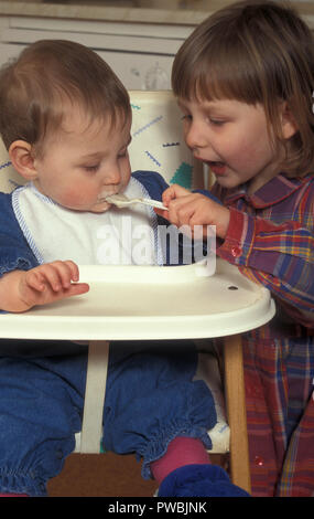 little girl spoonfeeding her baby sister Stock Photo