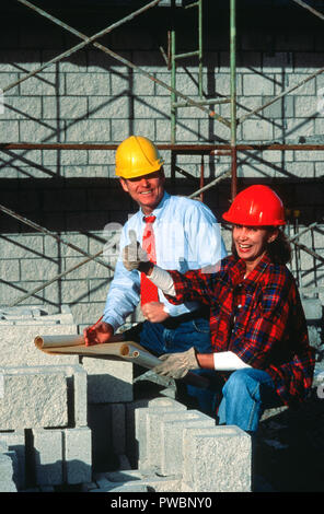 Supervisor confers with female construction worker on site, USA Stock Photo