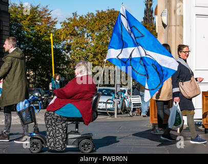 Disabled older woman in mobility scooter and saltire Yes Scottish Independence flag at All Under One Banner march, Royal Mile, Edinburgh, Scotland, UK Stock Photo