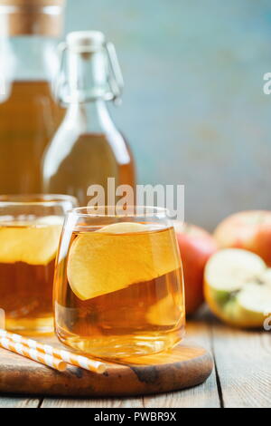 Organic Apple cider or juice on a wooden table with copy space. Two glasses with drink and autumn leaves on rustic background. Stock Photo