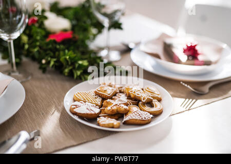 Gingerbread biscuits on a table set for a dinner at home at Christmas time. Stock Photo