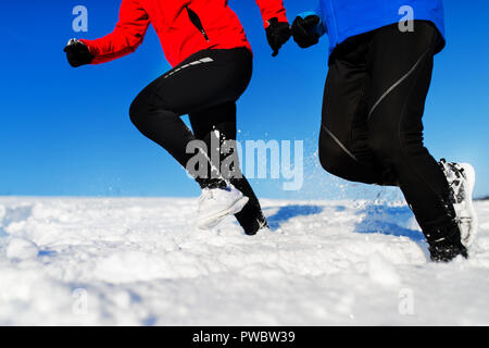 Feet of unrecognizable senior couple jogging in snowy winter nature. Stock Photo