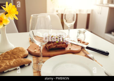 Dinner setting for two served in kitchen. Modern kitchen design. Roasted meat with wine prepared in dining room. Stock Photo