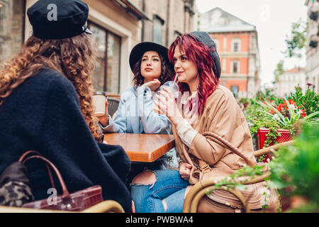 Three female friends having drinks in outdoor cafe. Women chatting and hanging together during coffee break Stock Photo