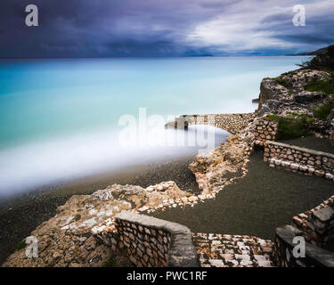 Seascape image taken with a long exposure of an old slave port in the Caribbean with dramatic clouds on the horizon Stock Photo