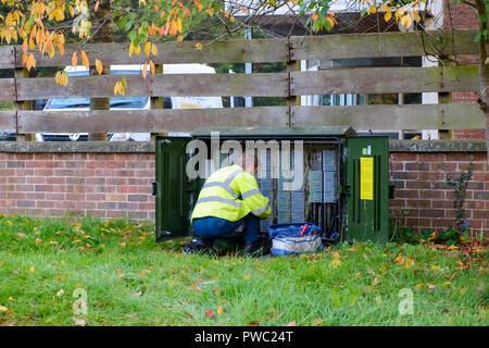 bt openreach telephone engineer kneeling in front of a wiring cabinet, kent, uk