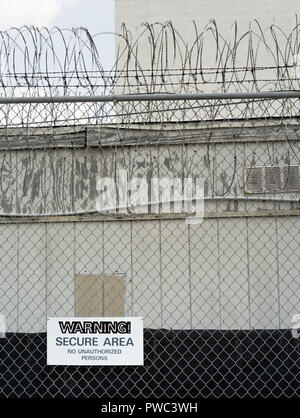 A high chan link fence surrounds a county jail in the deep south with a warning sign Stock Photo