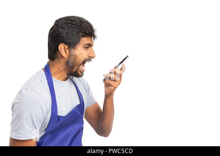 Angry indian hypermarket or supermarket male employee yelling at phone with open mouth isolated on white studio background Stock Photo