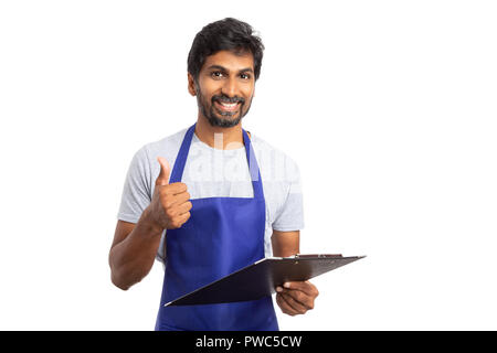 Indian hypermarket manager smiling with thumb up holding clipboard as approved gesture isolated on white studio background Stock Photo