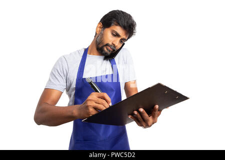 Very busy hypermarket or supermarket employee talking on the phone and checking clipboard writing isolated on white background Stock Photo