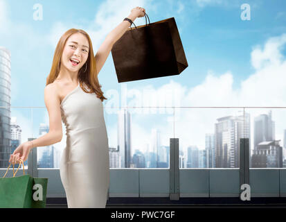 Attractive chinese woman with colorful paper bags on shopping mall. Black friday concept Stock Photo