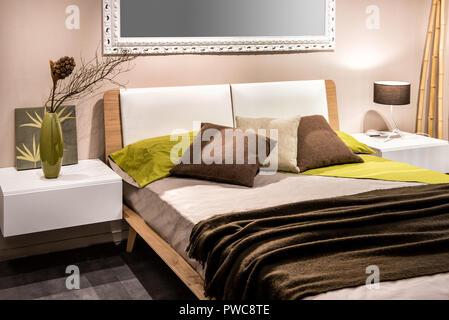 Bedroom interior with four pillows on bed and mirror on wall Stock Photo