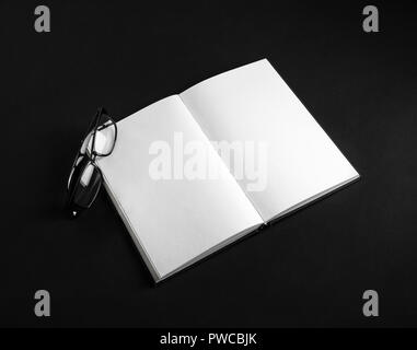 Mockup of opened blank notebook and glasses on black background. Responsive design template. Stock Photo