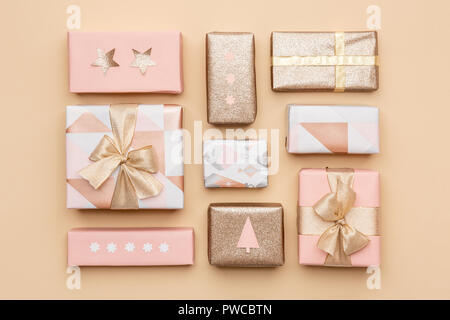 Gift wrapping composition. Beautiful nordic christmas gifts isolated on gold background. Pink and gold colored wrapped xmas boxes. Stock Photo