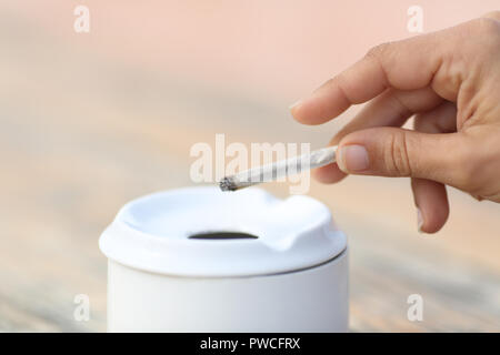 Close up of a woman smoking holding a hand made cigarette throwing the ash into the ashtray Stock Photo