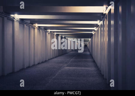 tunnel, underground pedestrian crossing at night. A long concrete tunnel with lanterns in the city underground. Underpass. Stock Photo