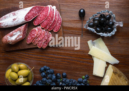 Mix of different snacks and appetizers. Spanish tapas on a wooden plate. Tapas bar. chorizo, olives, sausage, cheese,grape. Top view, Snack to wine Stock Photo