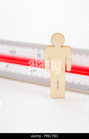 Macro small laser-cut wooden figure and ruler. Metaphor measuring personal performance, demographics concept, productivity, get the measure of a man. Stock Photo
