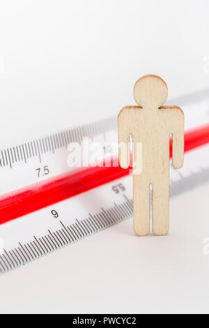 Macro small laser-cut wooden figure and ruler. Metaphor measuring personal performance, demographics concept, productivity, get the measure of a man. Stock Photo
