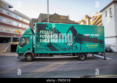 Large Evans Cycles green delivery lorry in Evans Cycles livery parked on the roadside making a delivery to their shop in Woking, Surrey, UK Stock Photo