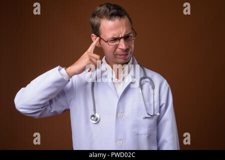 Studio shot of man doctor against brown background Stock Photo