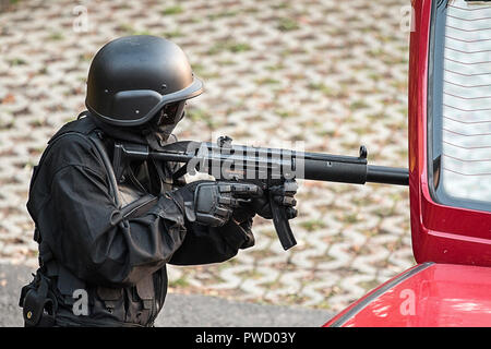 An armed and masked special units operator checks a vehicle. Stock Photo