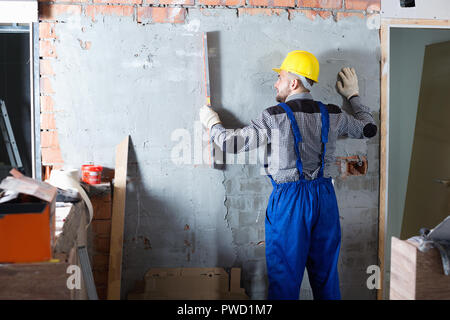 Diligent  builder is working with level near the wall at the object indoors Stock Photo