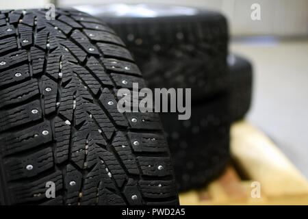 Snow tires with metal studs in garage. Small stones in the groove. Close up image, shallow depth of field. Stock Photo