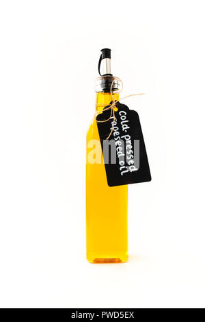 Rapeseed oil in a tall rectangular glass bottle with stainless steel pour spout, decorated with a black paper tag and jute bow, isolated on white back Stock Photo