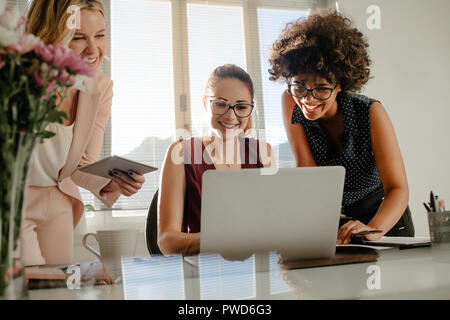 Three business women working together in the office and smiling. Female colleagues enjoying working together in office. Stock Photo