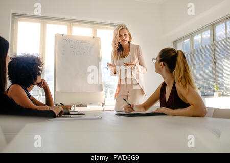 Female manager discussing over budget and income with colleagues during a board meeting. Group of businesswomen having meeting over finance. Stock Photo