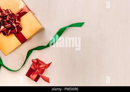 Gift boxes with ribbon on wooden background. Gift boxes wrapped coloured paper tied with ribbon with copy space on beige background. Flat lay concept. Stock Photo