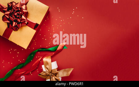 Present boxes and stars confetti with ribbons on red background. Flat lay composition for christmas with copy space for your text. Stock Photo