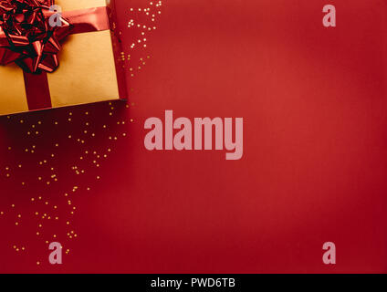 Golden coloured gift box with stars on red background. Top view of christmas gift with stars flat lay on red background. Stock Photo
