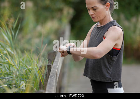 sporty woman checking her fitness tracker 'fit bit' on her wrist